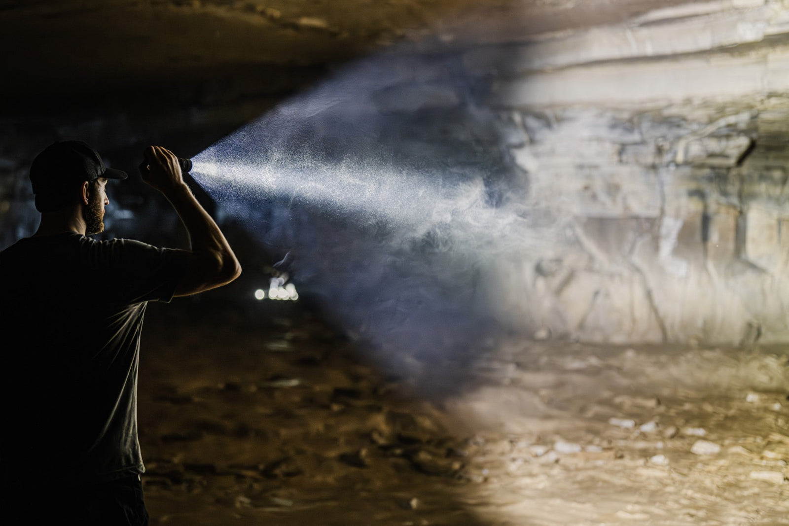 Man shining MCH Duty flashlight into a cave