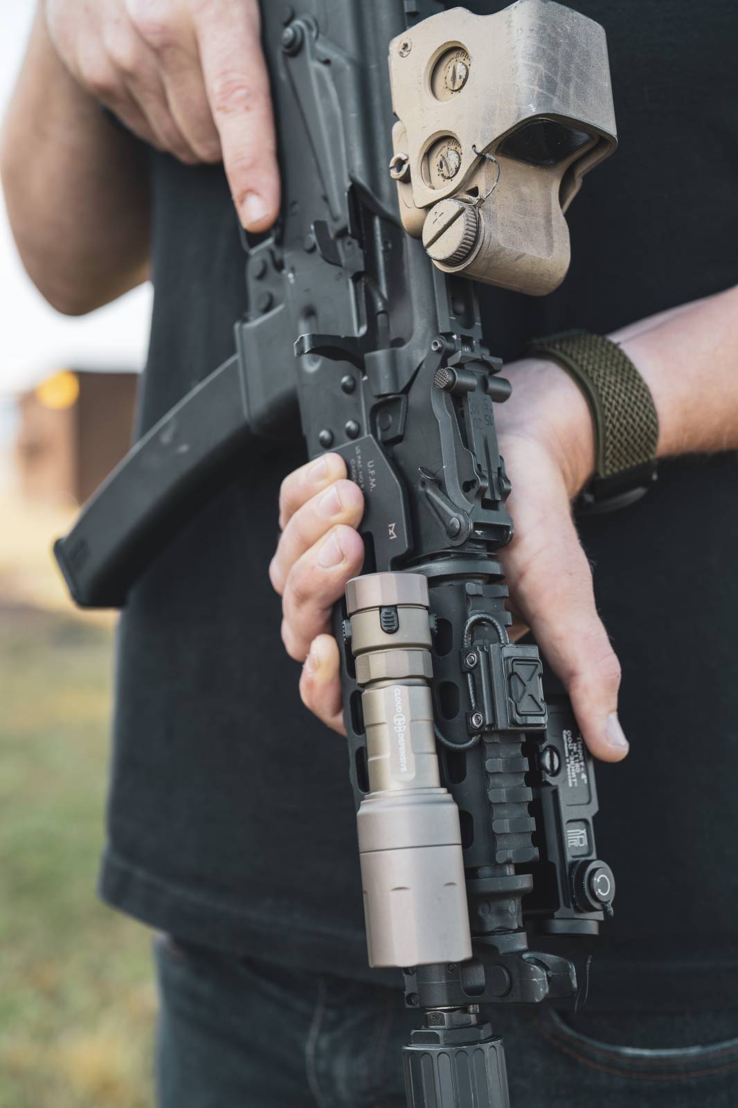 Man holding rifle with FDE Rein Micro flashlight.