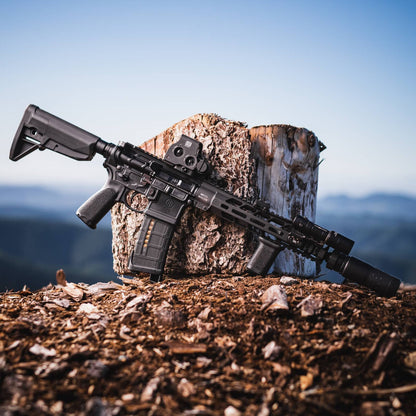 Black rifle with black Rein Micro flashlight leaning on tree stump.